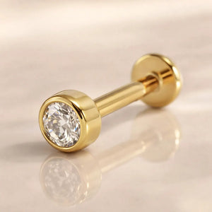 14k yellow gold 2.5mm diamond bezel-set flat back labret, angled view on warm neutral surface