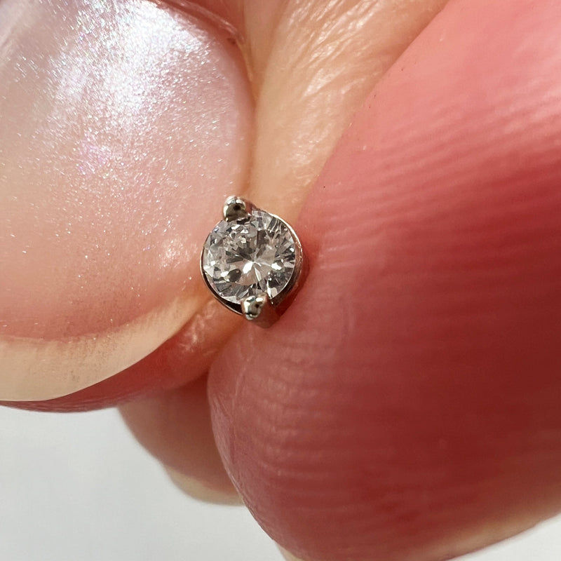 Duo-prong VS1 diamond threadless stud end held between fingers to show tiny actual size