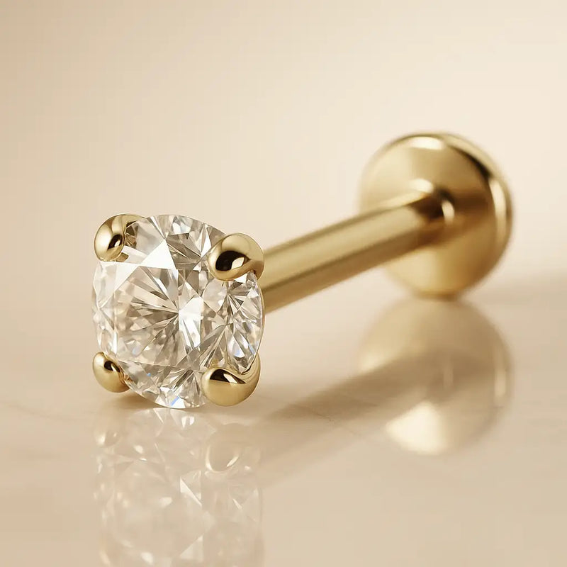 Close-up of 2.5mm CZ in 4-prong martini setting on 14k yellow gold flat back labret, warm background