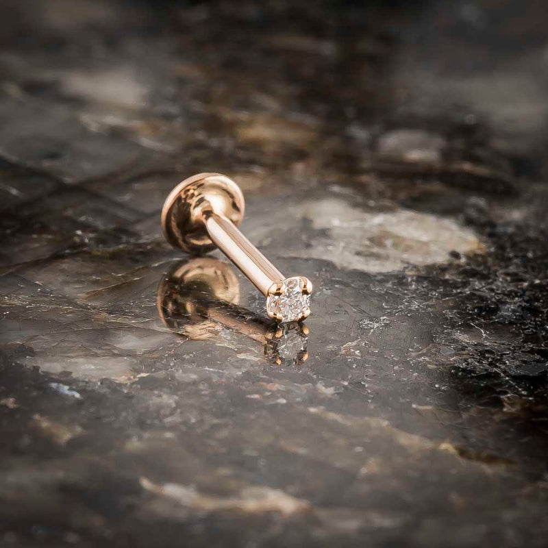 14k rose gold 2mm diamond flat back labret stud on dark stone surface, atmospheric lifestyle shot