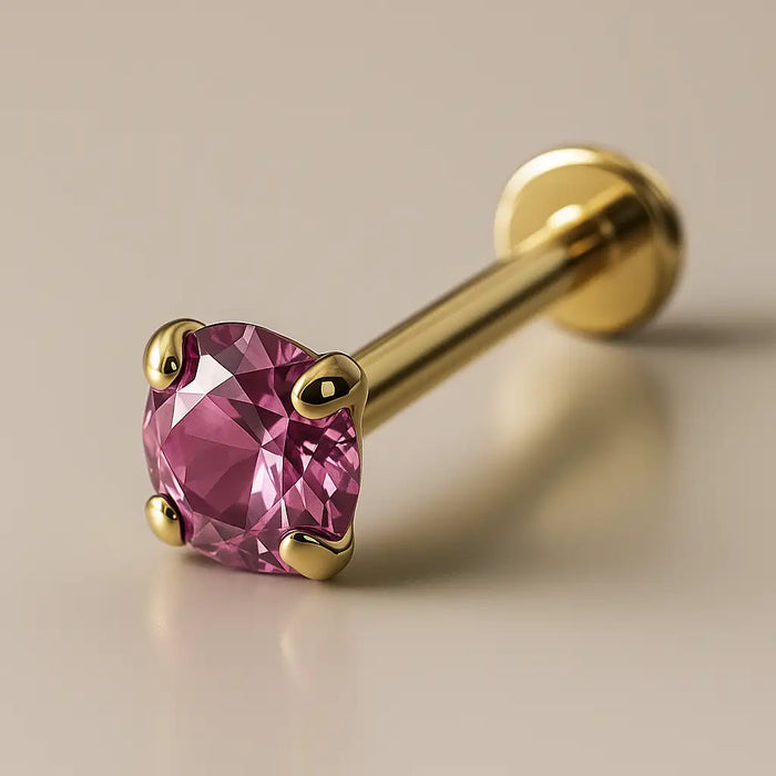 14K yellow gold flat back labret with 2mm pink sapphire in four-prong setting, angled studio view