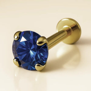 14K yellow gold flat back labret with 3mm blue sapphire in four-prong setting, angled product view