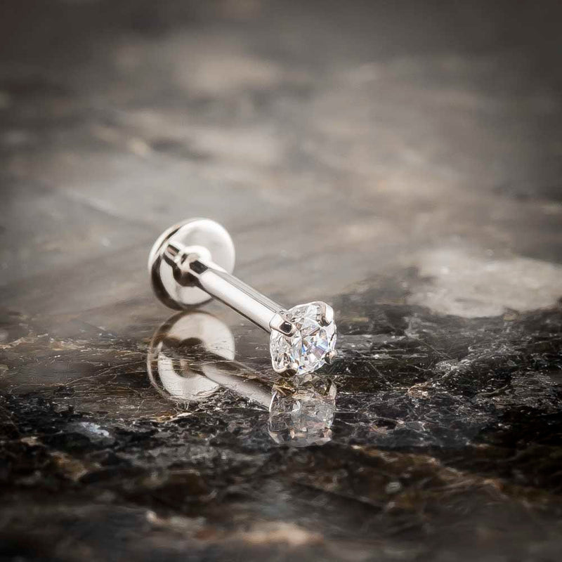 14k white gold 3mm diamond flat back labret stud on dark marble surface, angled lifestyle shot
