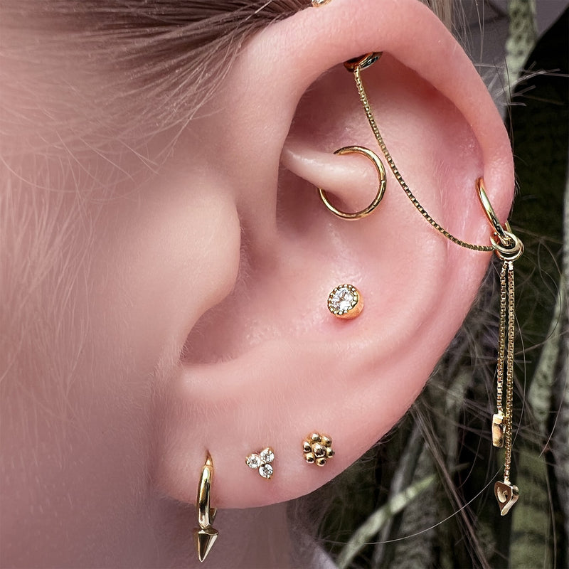 14k gold flower stud end worn in lobe piercing, styled with mixed gold ear stack on model