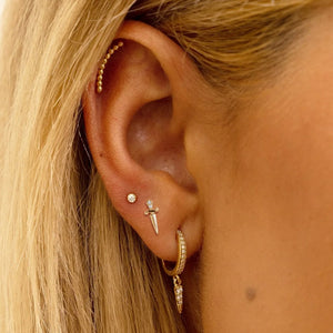 Diamond dagger earring worn in second lobe piercing, styled with curated gold ear stack on model