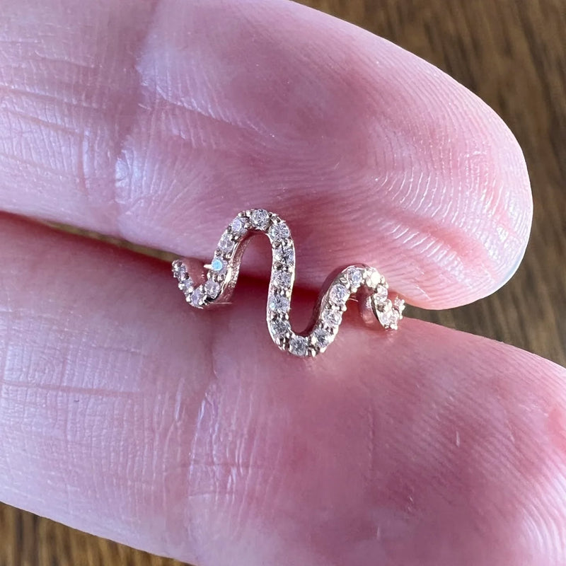 14k rose gold Cosmo CZ seam ring held between fingers for size reference