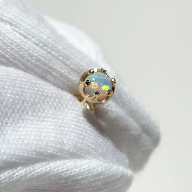 White gloves holding Reina crown setting with a 4mm Ethiopian opal