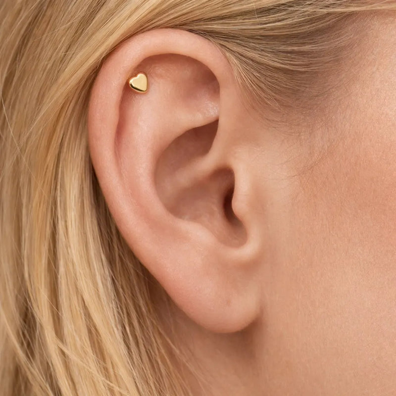 14K yellow gold heart flat back earring worn in helix cartilage piercing on model