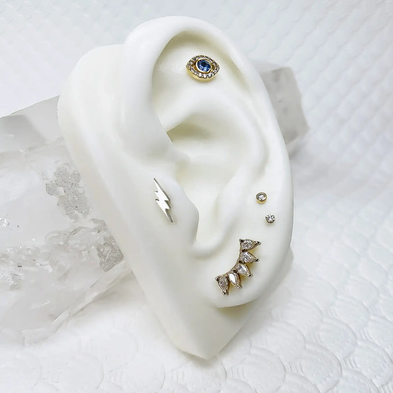 14k yellow gold white sapphire crescent climber on ceramic ear display in curated stack