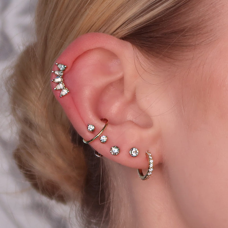 Lumina diamond flat back stud worn in lobe piercing as part of a layered gold ear stack with multiple styles