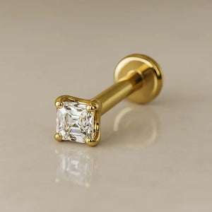 14k yellow gold 2mm Asscher-cut diamond flat back labret stud, angled lifestyle shot on neutral surface