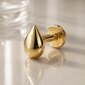 14k yellow gold droplet flat back labret stud with mirror-polish finish, angled lifestyle shot