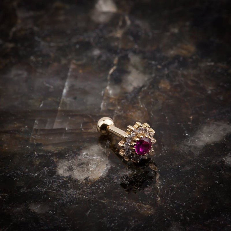 14k yellow gold ruby and CZ cluster flat back stud resting on dark stone surface