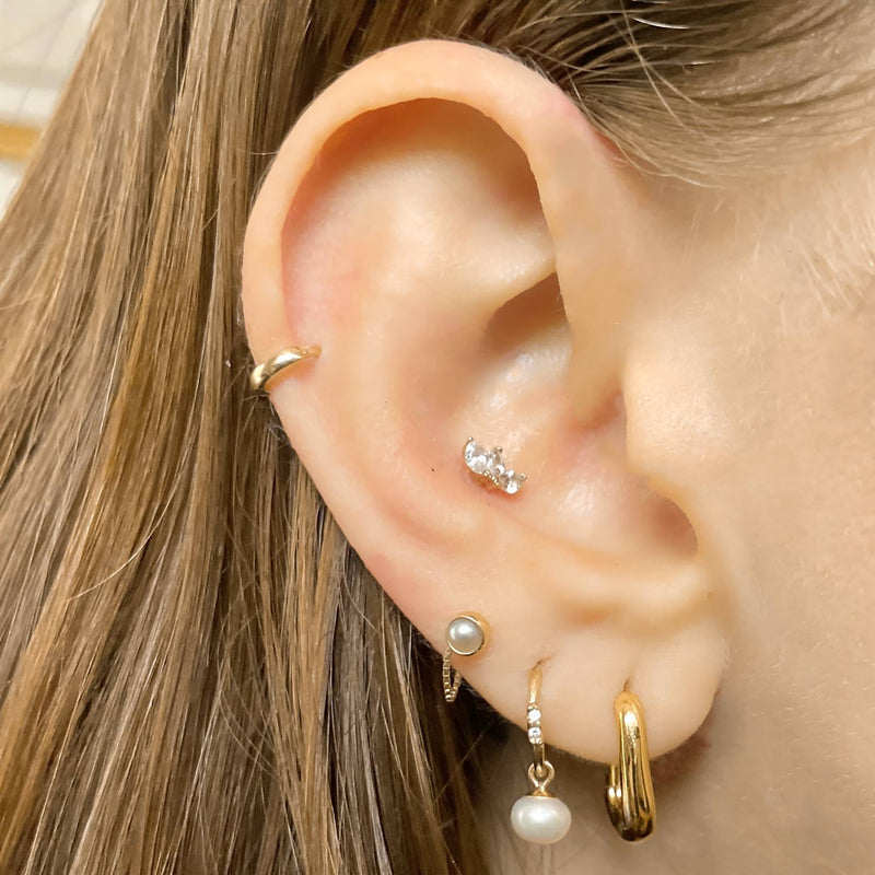 Pearl charm add-on worn on gold hoop lobe piercing, shown styled with multiple ear piercings