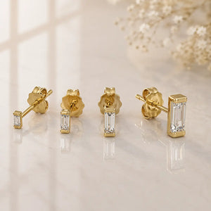 14K yellow gold baguette diamond stud earrings in four sizes displayed on marble surface