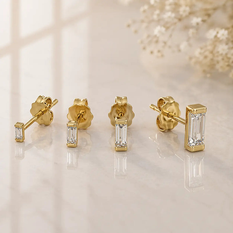 14K yellow gold baguette diamond stud earrings in four sizes displayed on marble surface