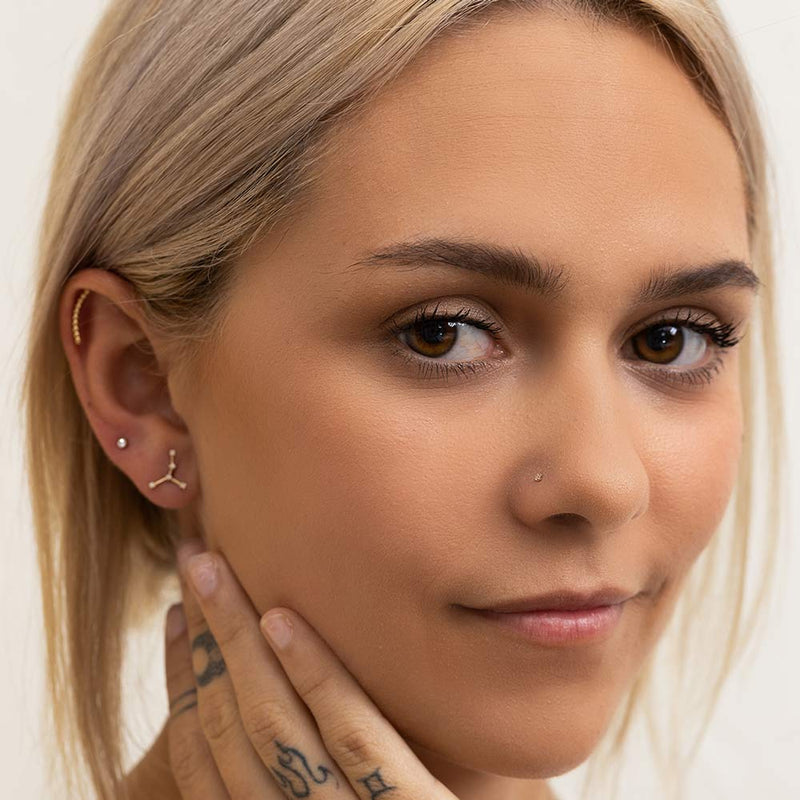 1.7mm CZ gold nose stud worn in piercing, front-facing model lifestyle shot