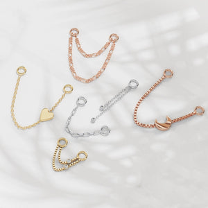Assorted 14K gold piercing chain connectors in yellow, white, and rose gold styles on marble surface