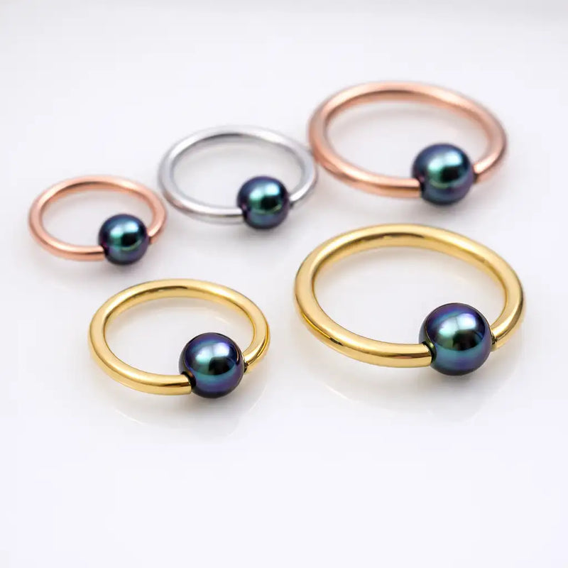 Peacock pearl captive bead rings in rose gold, silver, and yellow gold shown in small and large sizes