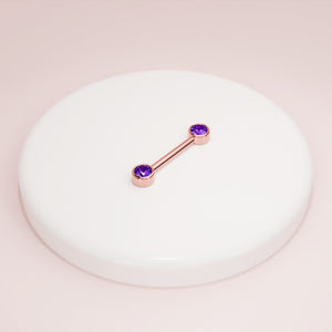 14K rose gold amethyst nipple barbell resting on white ceramic dish, styled product shot