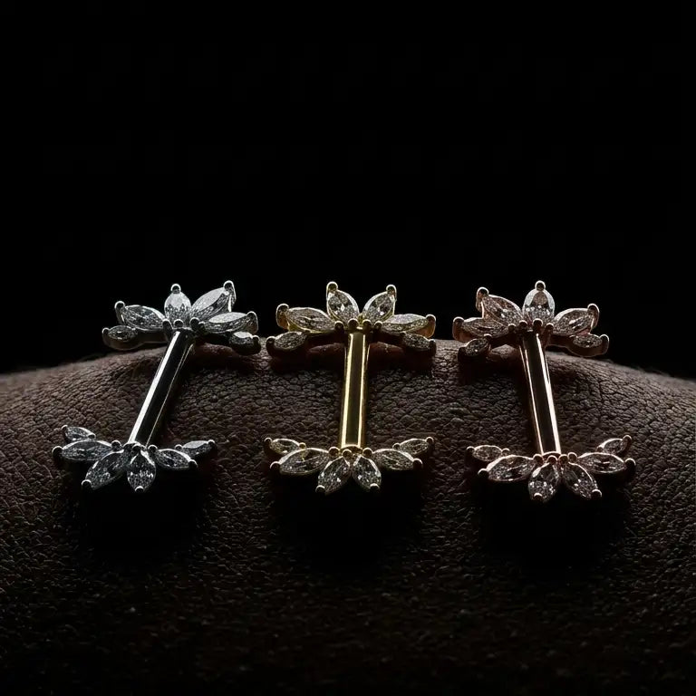 Three pairs of nipple barbells on a dark textured surface with a black background