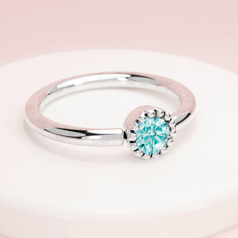 14k white gold aqua diamond captive bead ring on display stand, lifestyle shot with pink background