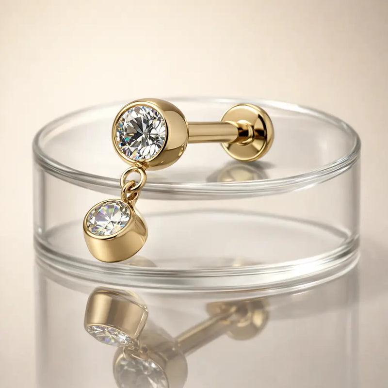 14k yellow gold bezel diamond dangle flat back stud resting on clear glass dish, lifestyle shot