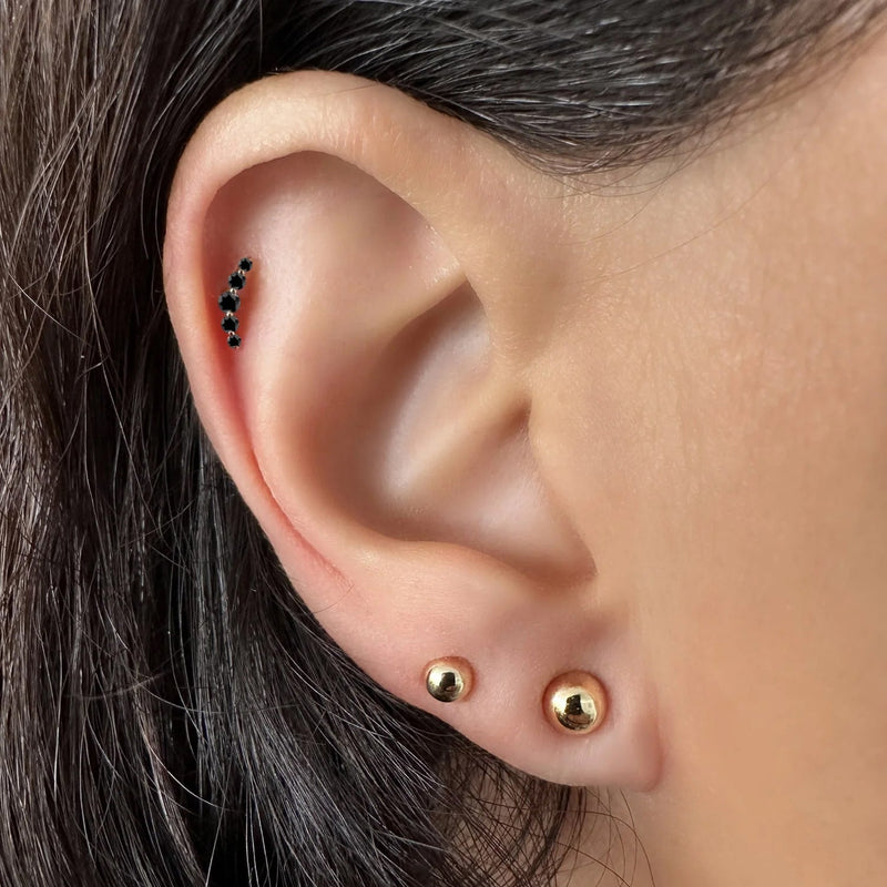 Black diamond mini climber stud shown in a helix cartilage piercing on model's ear