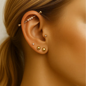 14k gold bubble gem industrial barbell shown in ear piercing, styled with multiple gold ear piercings