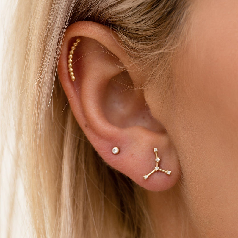 Close-up of Virgo constellation gold flat back labret in model's earlobe piercing for fit reference