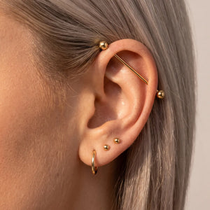 Model wearing a 14K gold Classic Industrial Barbell in an ear industrial piercing