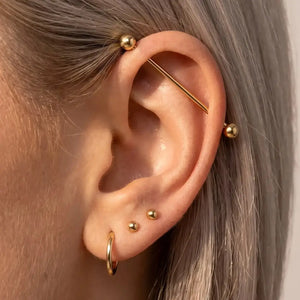 Model wearing a 14K gold Classic Industrial Barbell in an ear industrial piercing
