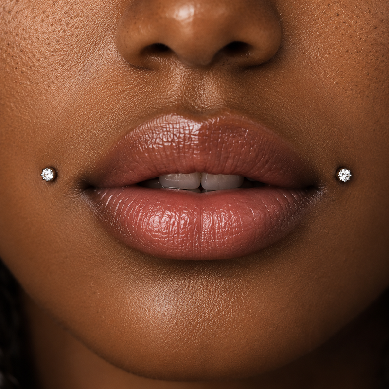 Dahlia piercing with a pair of prong-set diamond studs, one at each corner of the mouth