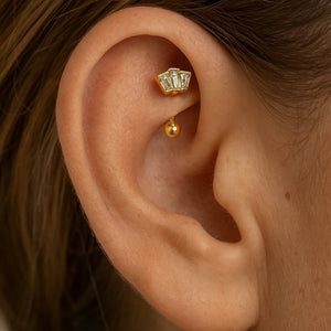 14k yellow gold deco fan curved barbell shown in a rook piercing, fan-shaped CZ top visible