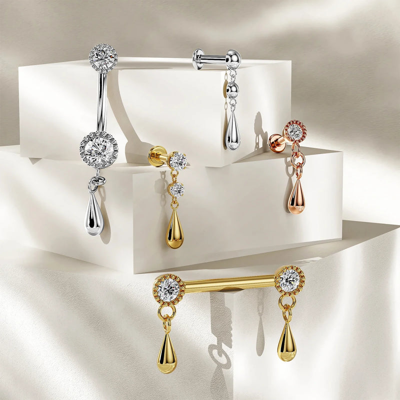Dew drop navel ring collection in 14K yellow, white, and rose gold with CZ settings displayed on pedestals