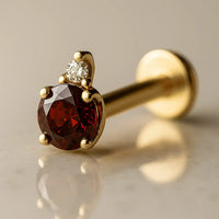 14k yellow gold garnet and diamond flat back labret, angled view showing prong-set red garnet with diamond accent