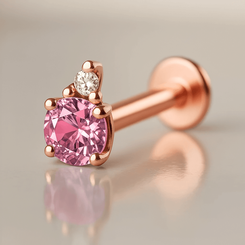 14k rose gold flat back labret with pink tourmaline and diamond accent, angled side view on reflective surface