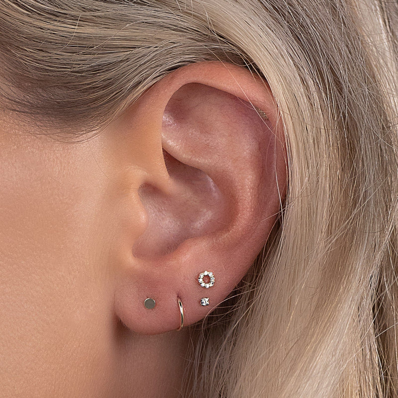 Small 14k yellow gold clicker hoop worn in second lobe piercing as part of minimalist ear stack