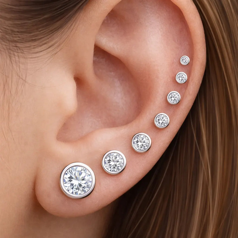 White gold bezel diamond flat back studs stacked across ear piercings in graduated sizes