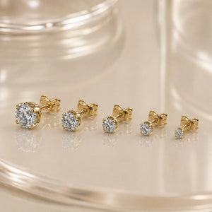 High-set diamond studs in various sizes displayed on a glass surface