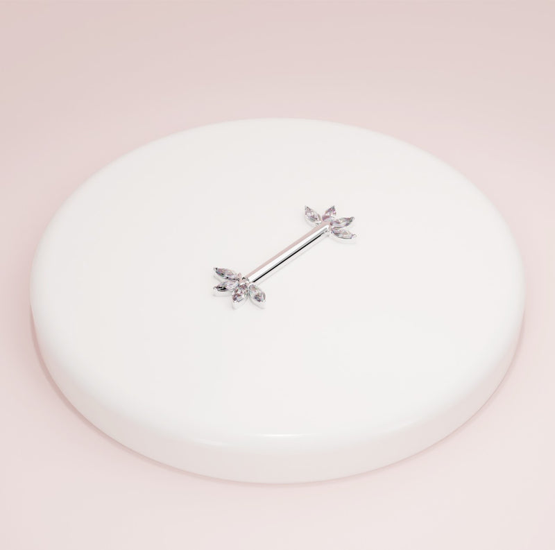 14K white gold marquise fan nipple barbell resting on white ceramic dish, angled view