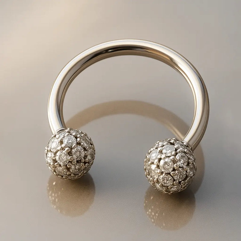 14K white gold diamond pavé circular barbell resting on reflective gray surface, angled view