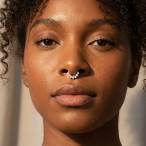 Diamond Petal 14K gold clicker ring worn in a septum piercing on a model, close-up showing the diamond-set petals sitting flush against the skin