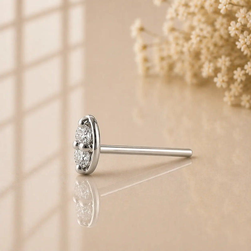 14K white gold double diamond nose stud straight post, side profile on warm reflective surface