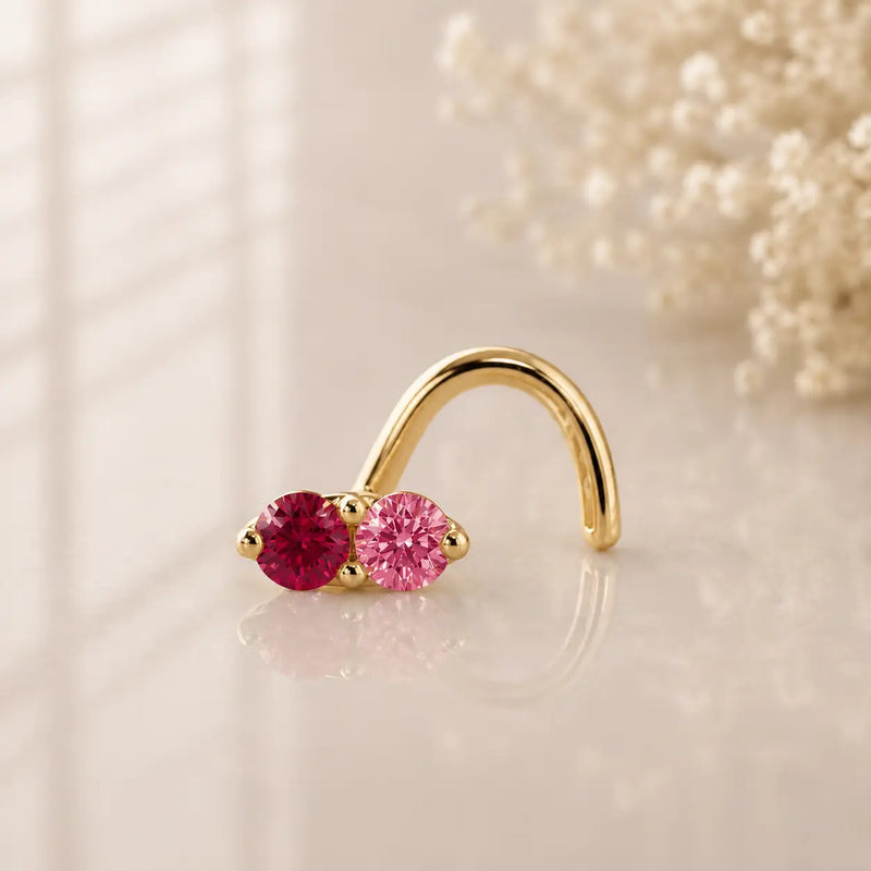 Ruby and pink sapphire, solid yellow gold nose twist, on a glass surface for a lifestyle photo.