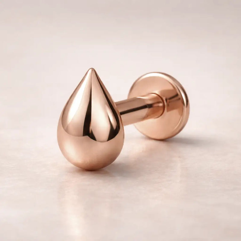 14k rose gold droplet flat back labret stud showing warm-toned mirror finish, side angle view