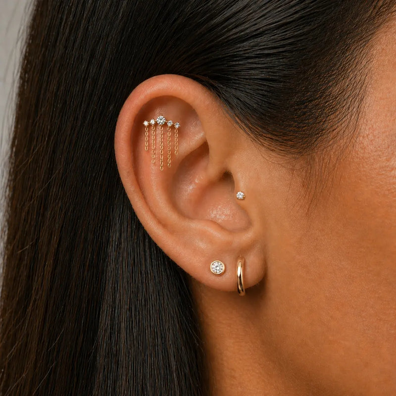 Model wearing a diamond climber flat back earring with chain dangles and a hoop and diamond studs.
