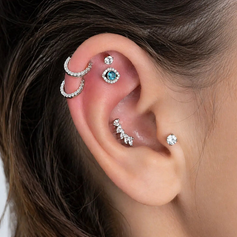 White gold evil eye blue topaz flat back stud in inner conch piercing, styled ear stack on model