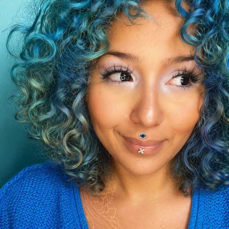 Evil eye diamond blue topaz labret stud worn as lip piercing on model with blue curly hair