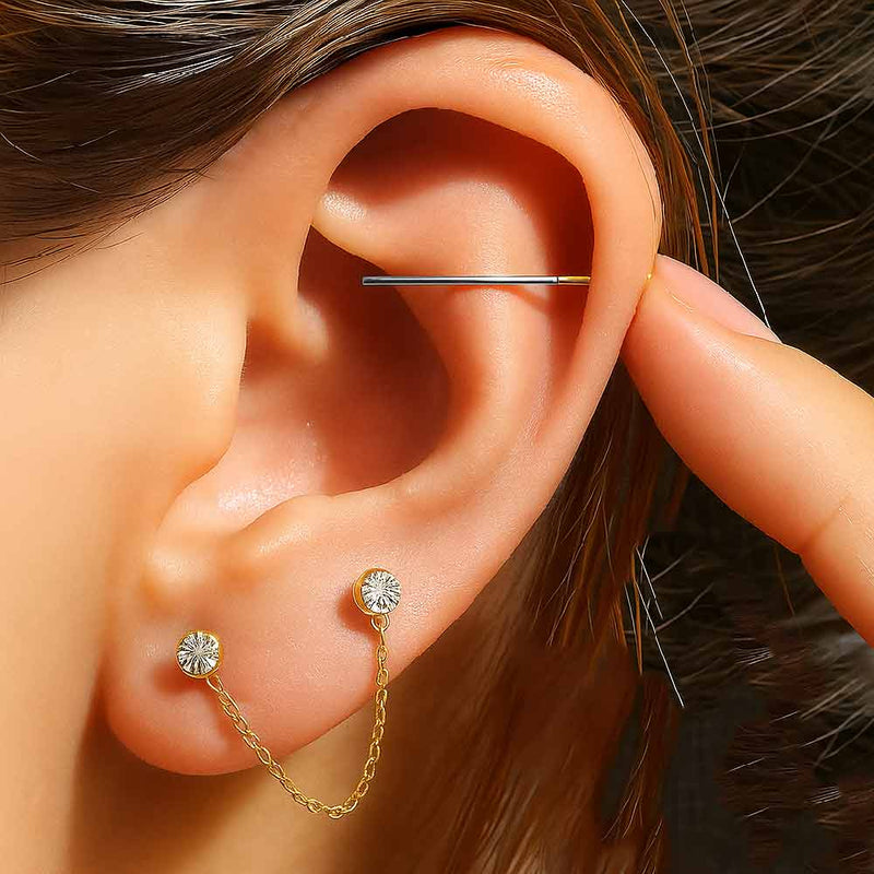Insertion tool being used in a helix piercing on a model, with gold CZ chain connector studs in lobe
